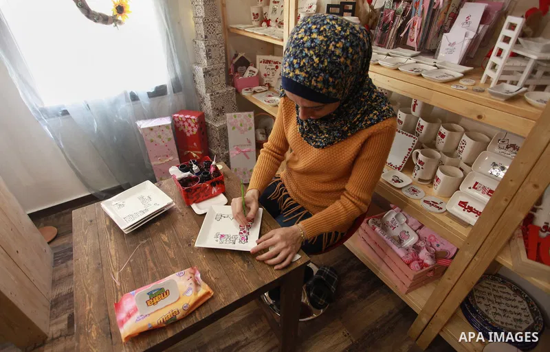 A Palestinian artist Dima Sha'sha'a "owner of Tezzkar Project" works at her shop in Gaza city on February 28, 2018. Dima and her brother Hamdi take the drawing on dishes, cardboard and glass as a job for nearly seven yea...