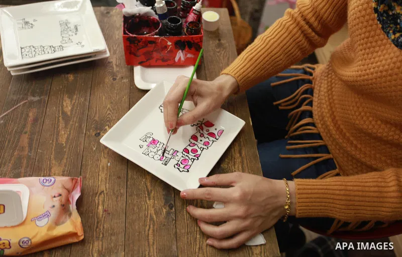 A Palestinian artist Dima Sha'sha'a "owner of Tezzkar Project" works at her shop in Gaza city on February 28, 2018. Dima and her brother Hamdi take the drawing on dishes, cardboard and glass as a job for nearly seven yea...