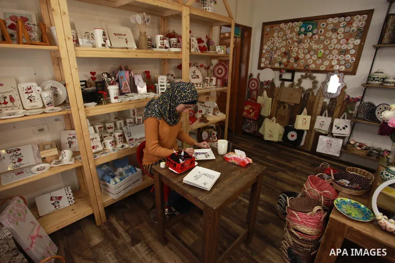 A Palestinian artist Dima Sha'sha'a "owner of Tezzkar Project" works at her shop in Gaza city on February 28, 2018. Dima and her brother Hamdi take the drawing on dishes, cardboard and glass as a job for nearly seven yea...