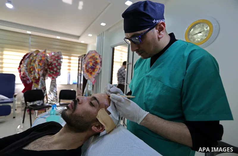 A Palestinian doctor Ahmed al-Moghrabi operates on a patient who undergo to Hair transplant surgery at his clinic, in Gaza city on February 28, 2018. Al-Moghrabi opened his clinic last year which is the first of its kind...