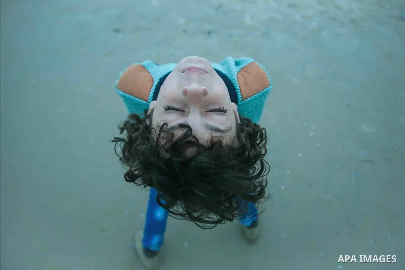 A boy with afro hairstyle with closed eyes have fun on the beach. Photo by Sanad Ltefa
