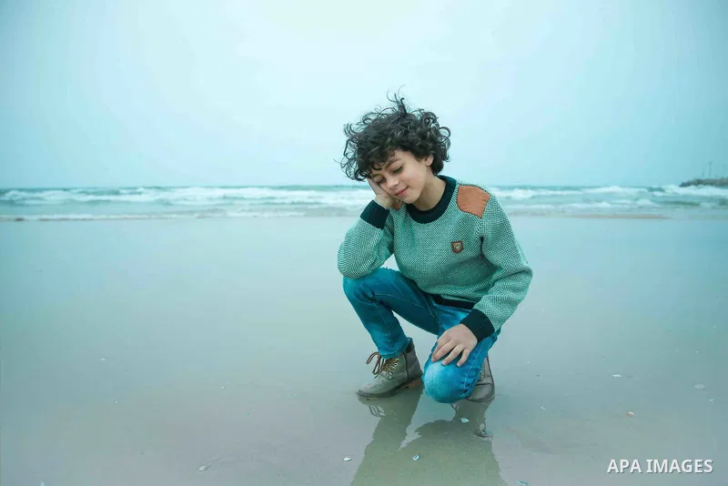 A boy with afro hairstyle have fun on the beach. Photo by Sanad Ltefa