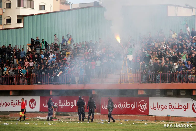 Palestinian fans light flares during a a football match between Palestinian Shabab Rafah football club players (in blue) and Shejaiya's football club players (in green) at Palestine Stadium in Gaza city on March 4, 2018....