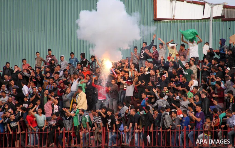 Palestinian fans light flares during a a football match between Palestinian Shabab Rafah football club players (in blue) and Shejaiya's football club players (in green) at Palestine Stadium in Gaza city on March 4, 2018....