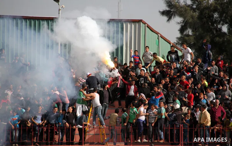 Palestinian fans light flares during a a football match between Palestinian Shabab Rafah football club players (in blue) and Shejaiya's football club players (in green) at Palestine Stadium in Gaza city on March 4, 2018....