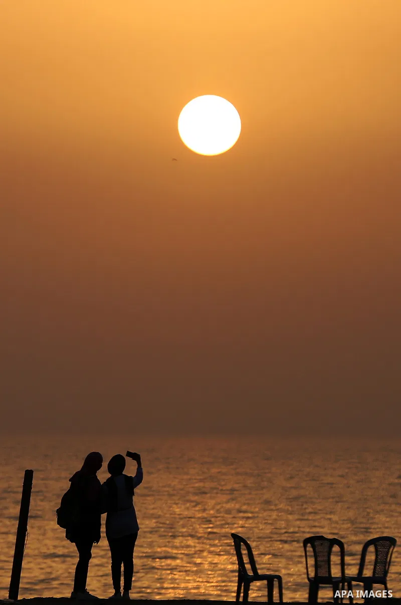 Palestinian girls take a selfie on the beach of Gaza city during sunset on March 5, 2018. Photo by Yasser Qudih