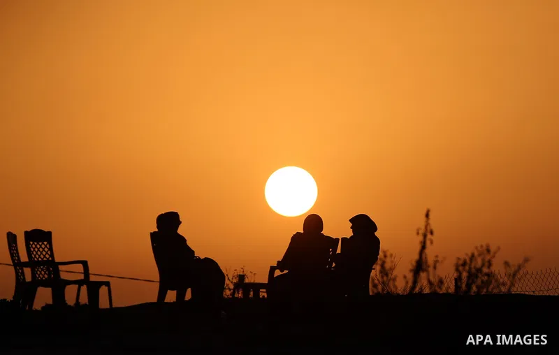 Palestinian women sit on the beach of Gaza city during sunset on March 5, 2018. Photo by Yasser Qudih