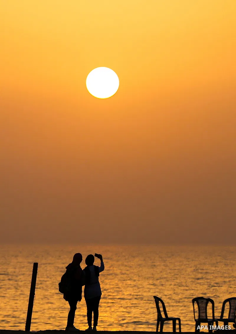 Palestinian girls take a selfie on the beach of Gaza city during sunset on March 5, 2018. Photo by Yasser Qudih