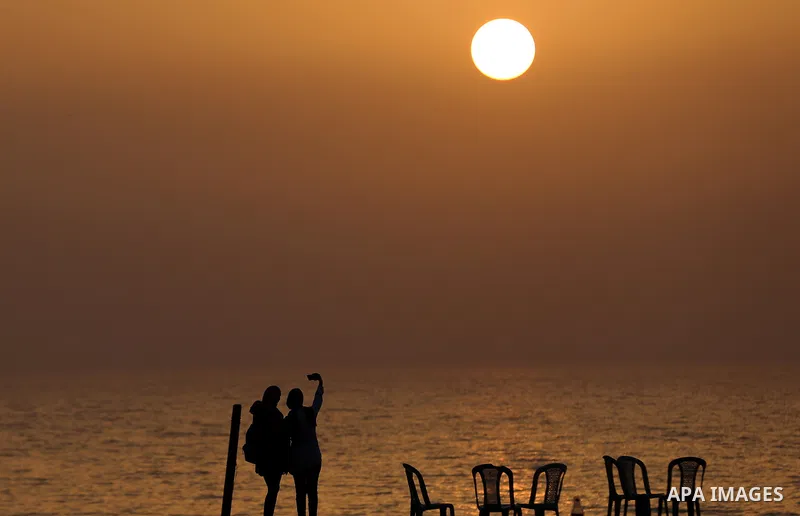 Palestinian girls take a selfie on the beach of Gaza city during sunset on March 5, 2018. Photo by Yasser Qudih