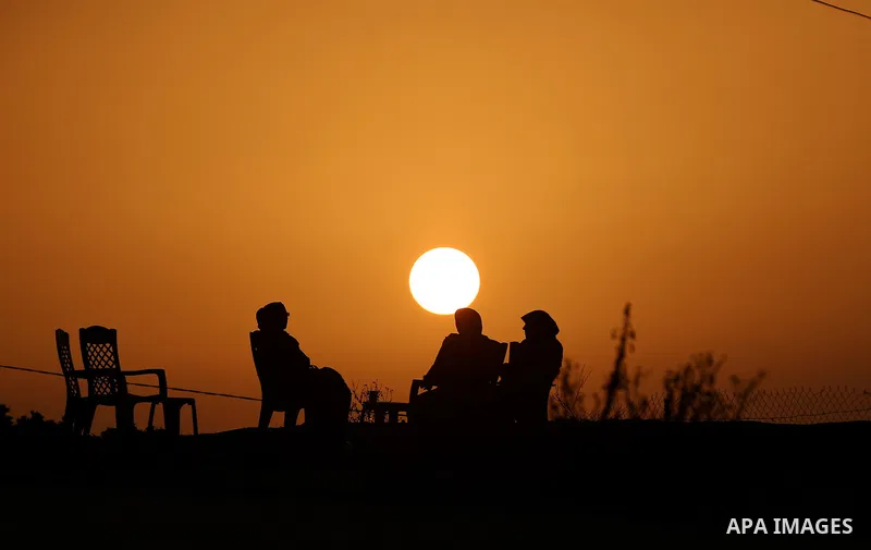 Palestinian women sit on the beach of Gaza city during sunset on March 5, 2018. Photo by Yasser Qudih