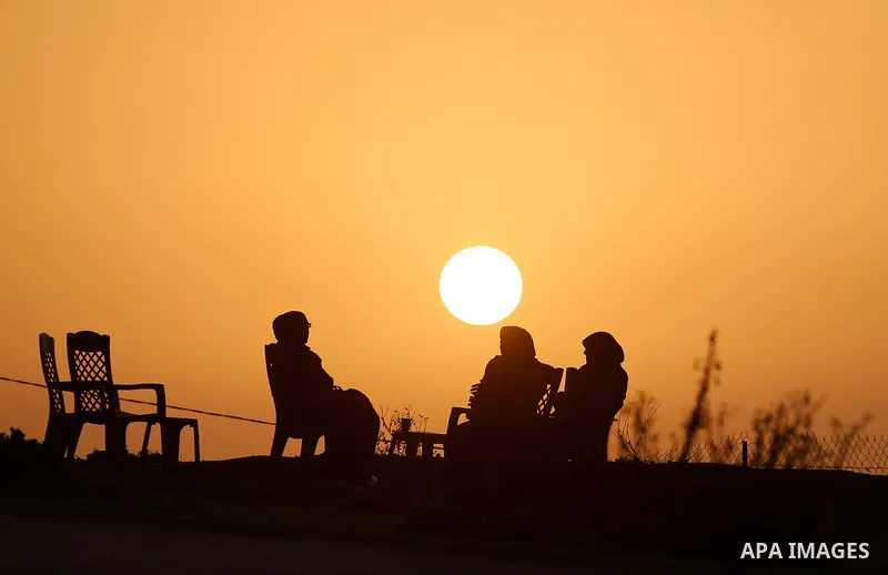 Palestinian women sit on the beach of Gaza city during sunset on March 5, 2018. Photo by Yasser Qudih