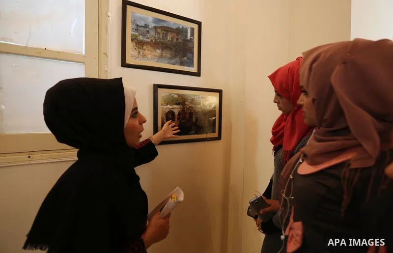 Palestinians attend exhibition of photographs for antique sites in Gaza city, on March 6, 2018. Photo by Ashraf Amra