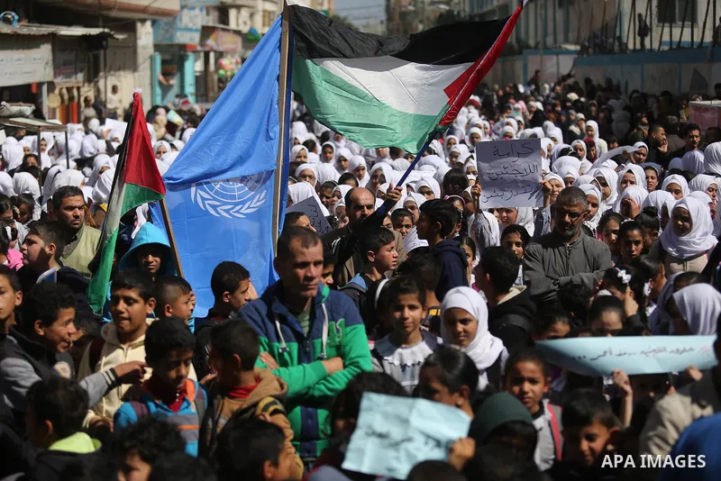 Palestinian school students shout slogans and hold placards in a protest against the US move to freeze funding for the UN agency for Palestinian refugees on March 7, 2018 at the al-Nusairat refugee camp, in central Gaza...