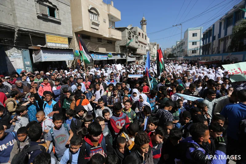 Palestinian school students shout slogans and hold placards in a protest against the US move to freeze funding for the UN agency for Palestinian refugees on March 7, 2018 at the al-Nusairat refugee camp, in central Gaza...