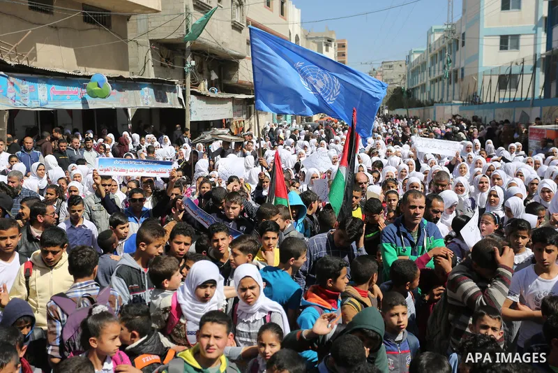 Palestinian school students shout slogans and hold placards in a protest against the US move to freeze funding for the UN agency for Palestinian refugees on March 7, 2018 at the al-Nusairat refugee camp, in central Gaza...