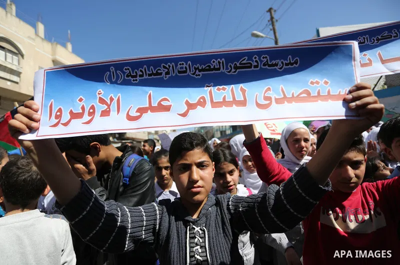 Palestinian school students shout slogans and hold placards in a protest against the US move to freeze funding for the UN agency for Palestinian refugees on March 7, 2018 at the al-Nusairat refugee camp, in central Gaza...