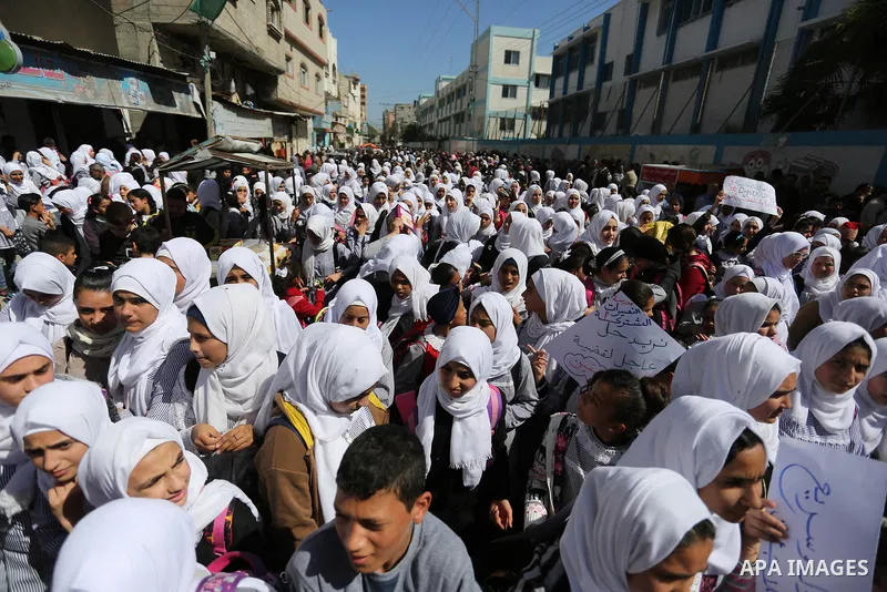 Palestinian school students shout slogans and hold placards in a protest against the US move to freeze funding for the UN agency for Palestinian refugees on March 7, 2018 at the al-Nusairat refugee camp, in central Gaza...