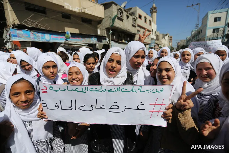 Palestinian school students shout slogans and hold placards in a protest against the US move to freeze funding for the UN agency for Palestinian refugees on March 7, 2018 at the al-Nusairat refugee camp, in central Gaza...