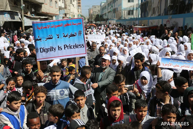 Palestinian school students shout slogans and hold placards in a protest against the US move to freeze funding for the UN agency for Palestinian refugees on March 7, 2018 at the al-Nusairat refugee camp, in central Gaza...