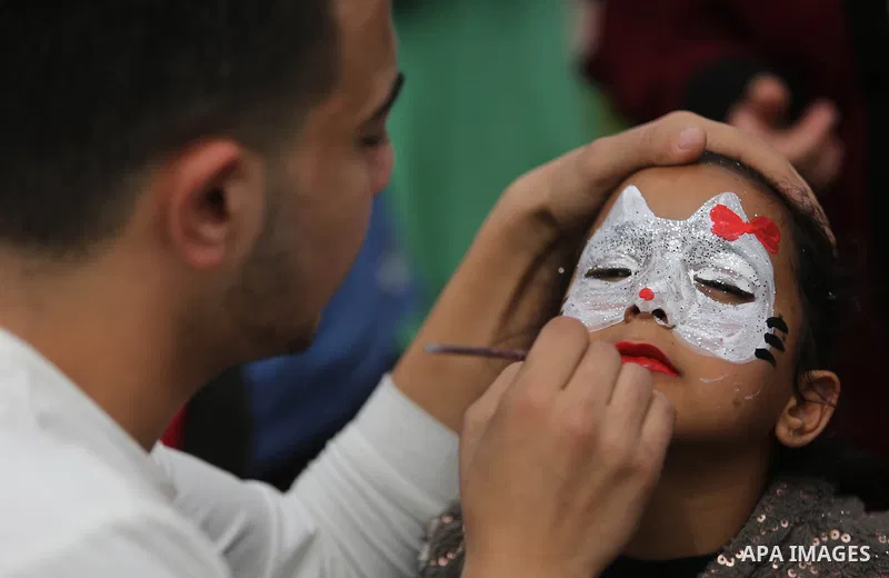A Palestinian man draws on a girl face during a celebrate on the occasion of International Women's Day in Gaza city, March 8, 2018. Photo by Ashraf Amra