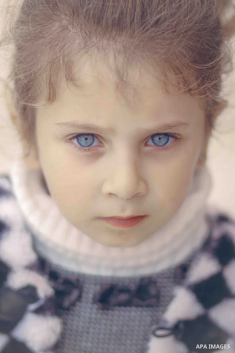 A blonde girl with blue eyes poses for a camera. Photo by Sanad Ltefa
