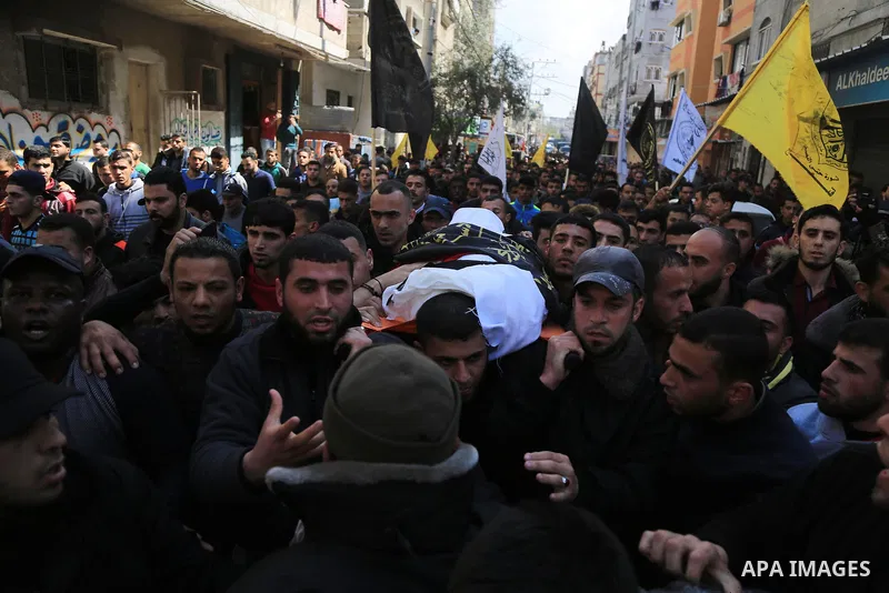 Palestinian mourners carry the body of a member of Palestinian Al-Quds Brigades militant Ibrahim Farhat, 29, who was died yesterday in an explosion during his funeral in Beit lahia in the northern Gaza Strip on March 11,...