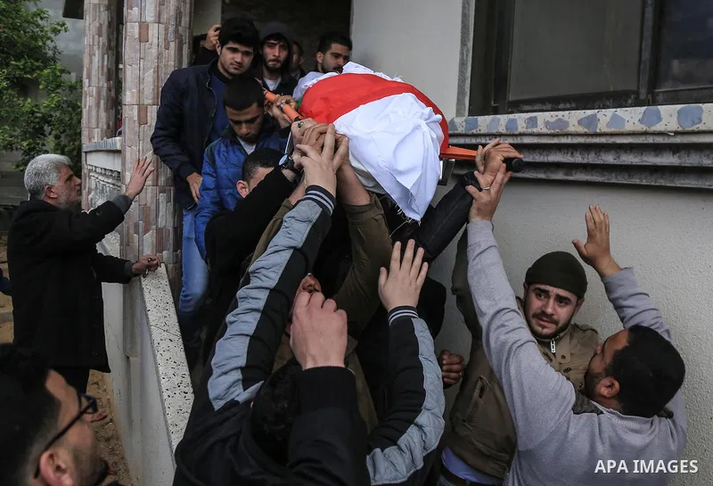 Palestinian mourners carry the body of a member of Palestinian Al-Quds Brigades militant Ibrahim Farhat, 29, who was died yesterday in an explosion during his funeral in Beit lahia in the northern Gaza Strip on March 11,...