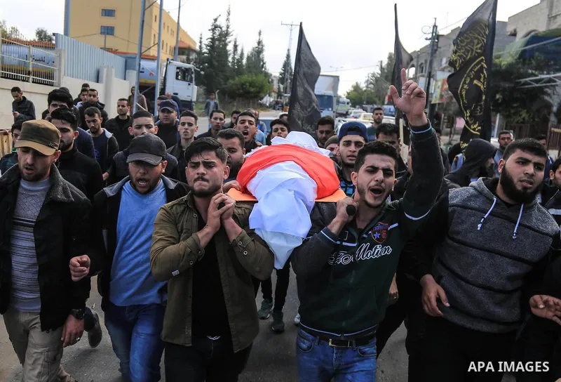 Palestinian mourners carry the body of a member of Palestinian Al-Quds Brigades militant Ibrahim Farhat, 29, who was died yesterday in an explosion during his funeral in Beit lahia in the northern Gaza Strip on March 11,...