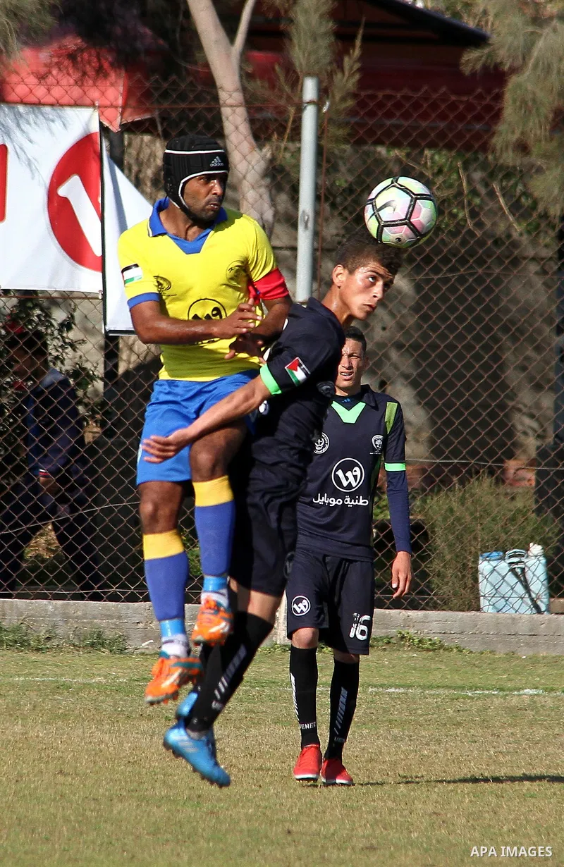 Palestinian Shabab Jabalia football club players (in yellow) and al-Hilal football club players (in black) compete during a football match at Beit Lahia Stadium in the northern Gaza Strip on March 11, 2018. Photo by Mahm...