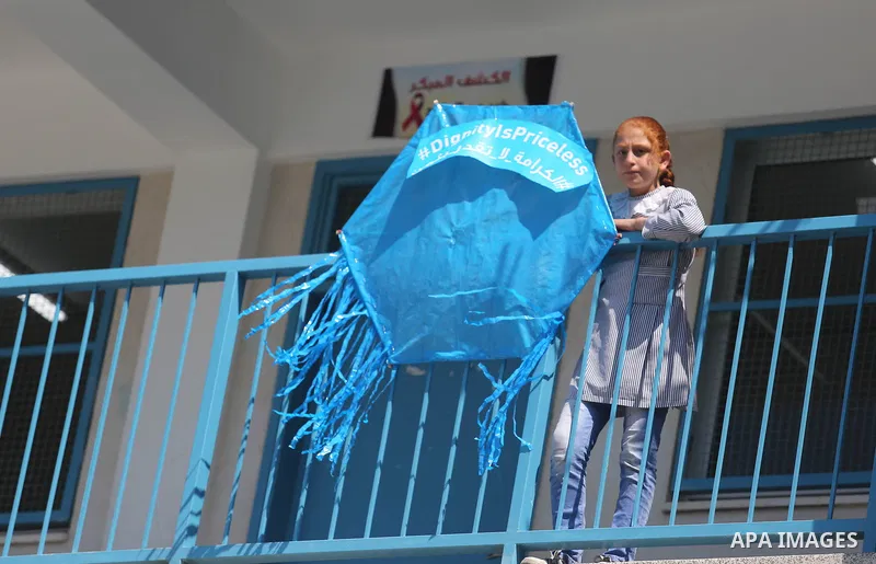 Palestinian schoolgirls fly kites during a protest against US aid cuts to mark the seventh anniversary of the Tohoku earthquake and tsunami that left more than 18,500 people dead or missing, at a school belonging to the...