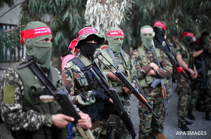 Palestinian militants of the National Resistance brigades, the armed wing of the Democratic Front for the Liberation of Palestine (DFLP), stand outside al-Shifa hospital after the arrival of the body of a Palestinian fis...