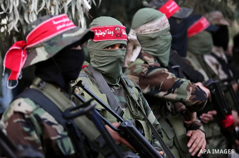 Palestinian militants of the National Resistance brigades, the armed wing of the Democratic Front for the Liberation of Palestine (DFLP), stand outside al-Shifa hospital after the arrival of the body of a Palestinian fis...