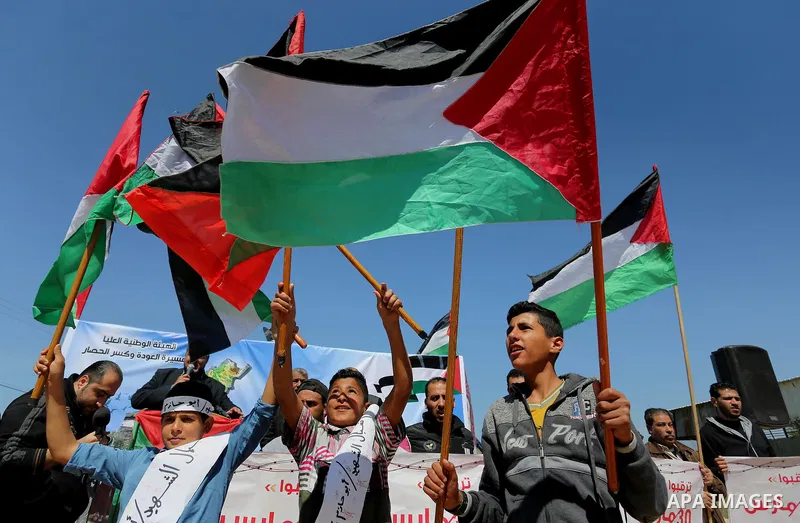 Palestinians hold placards and the national flags during a rally against "Deal of the Century" and to announce the launch of the great return march near the border with Israel in east of Gaza city on March 17, 2018. Phot...