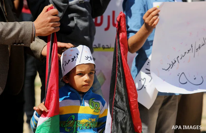 Palestinians hold placards and the national flags during a rally against "Deal of the Century" and to announce the launch of the great return march near the border with Israel in east of Gaza city on March 17, 2018. Phot...