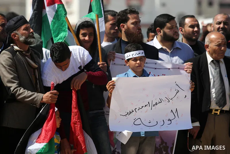 Palestinians hold placards and the national flags during a rally against "Deal of the Century" and to announce the launch of the great return march near the border with Israel in east of Gaza city on March 17, 2018. Phot...