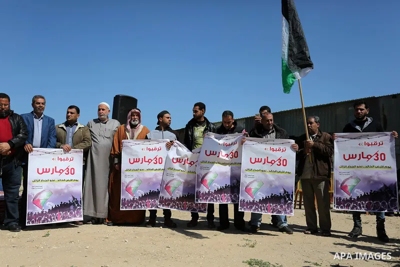 Palestinians hold placards and the national flags during a rally against "Deal of the Century" and to announce the launch of the great return march near the border with Israel in east of Gaza city on March 17, 2018. Phot...
