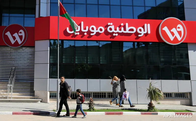 Palestinians walk passed closed doors of Wataniya Mobile headquarter in Gaza City on March 17, 2018. Palestinian police in Gaza closed of Wataniya Mobile headquarter today by order attorney general in Gaza strip on the b...
