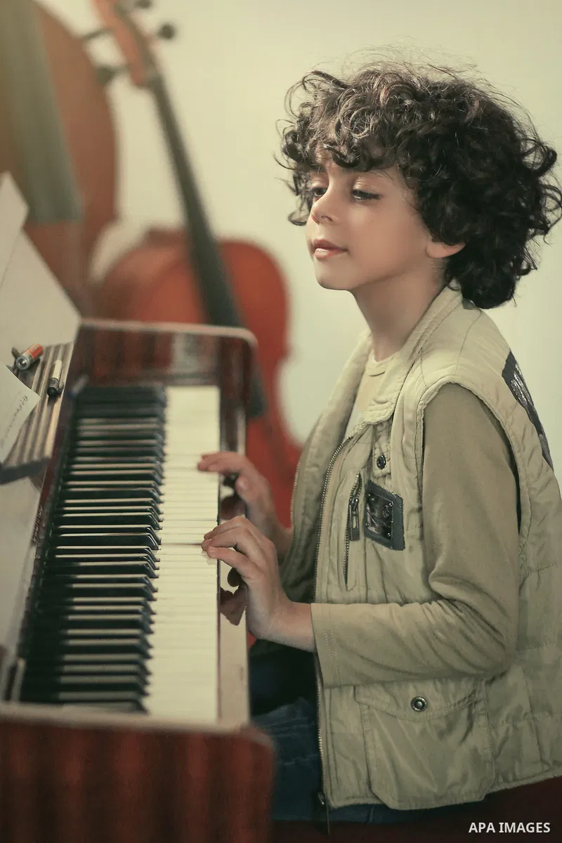 A boy plays on piano. Photo by Sanad Ltefa