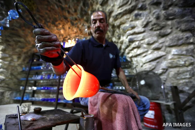 A Palestinian Yaacqoub al-Natsheh, professional glassblower who has been forming glass for over 40 years, works at his new workshop near the Ibrahimi Mosque, in the West Bank city of Hebron, March 25, 2018. Photo by Wisa...