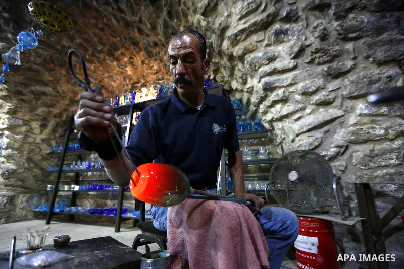 A Palestinian Yaacqoub al-Natsheh, professional glassblower who has been forming glass for over 40 years, works at his new workshop near the Ibrahimi Mosque, in the West Bank city of Hebron, March 25, 2018. Photo by Wisa...