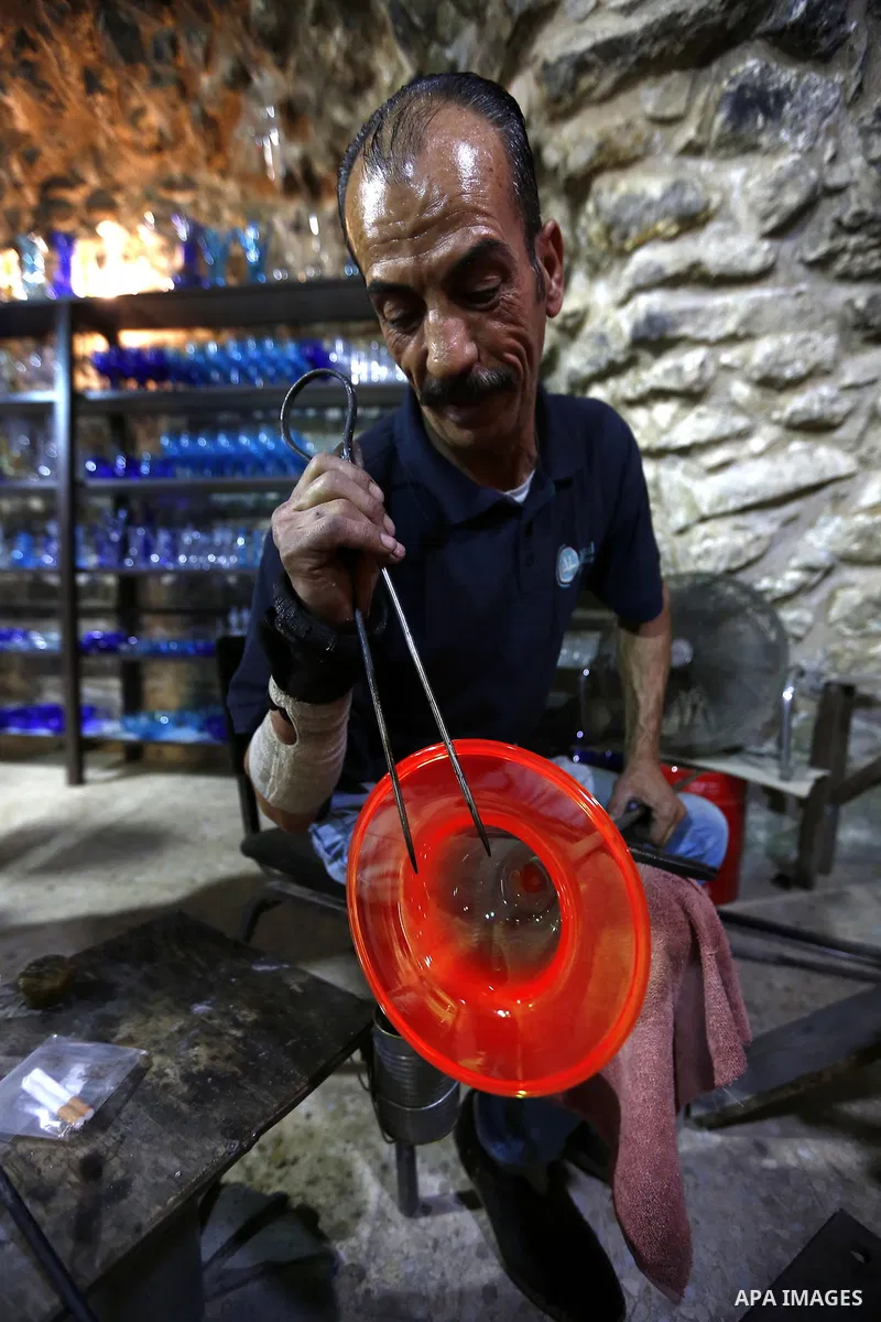 A Palestinian Yaacqoub al-Natsheh, professional glassblower who has been forming glass for over 40 years, works at his new workshop near the Ibrahimi Mosque, in the West Bank city of Hebron, March 25, 2018. Photo by Wisa...