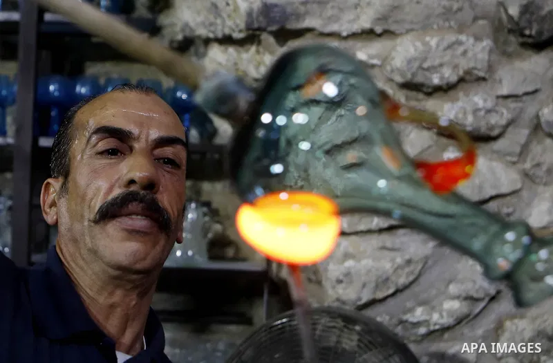 A Palestinian Yaacqoub al-Natsheh, professional glassblower who has been forming glass for over 40 years, works at his new workshop near the Ibrahimi Mosque, in the West Bank city of Hebron, March 25, 2018. Photo by Wisa...