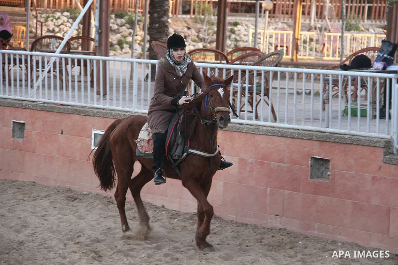 A Palestinian woman rides her horse during a training in preparation of equestrian competition in Gaza city on March 26, 2018. Photo by Mahmoud Ajour