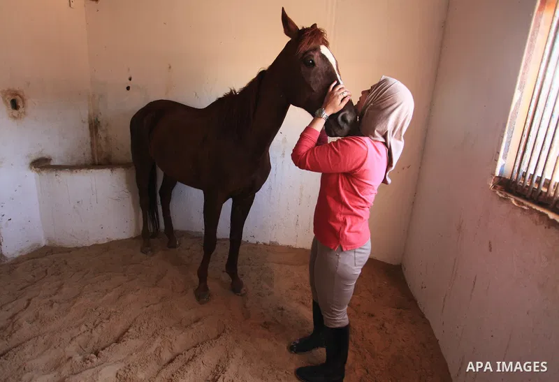 Palestinian woman Afnan al-Hayek, 31, plays with her horse during a training, in Gaza city on March 26, 2018. Al-Hayek participated in many equestrian competitions and she seeks to represent Palestine in international fo...