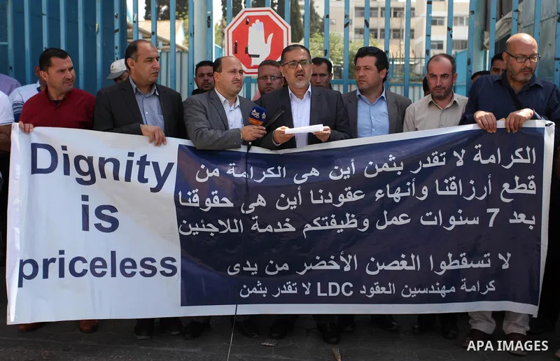 Palestinian engineers hold banners during a protest demanding their rights in front of the headquarters United Nations Relief and Works Agency (UNRWA) in Gaza city, March 27, 2018. Photo by Mahmoud Ajour