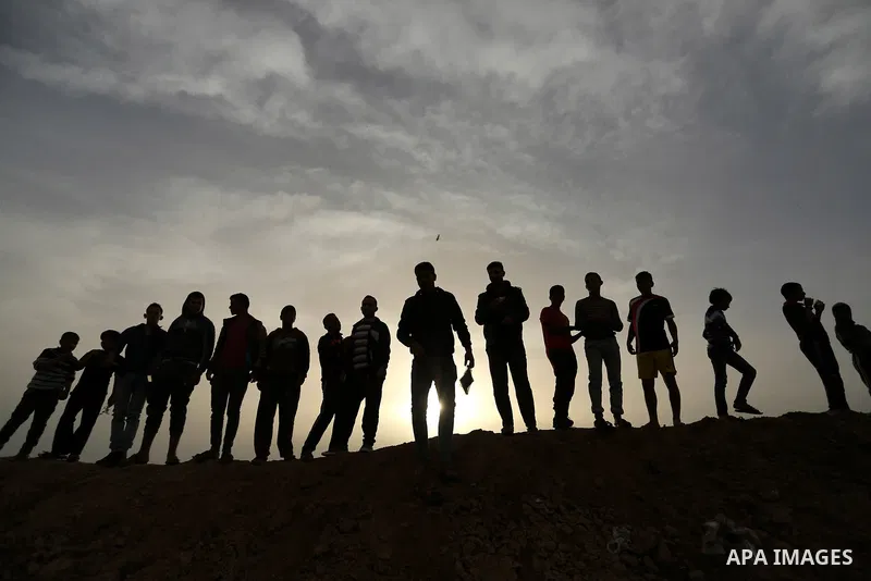 Palestinians stand near the Gaza-Israel border on the outskirts of Khan Yunis in the southern Gaza Strip on March 28, 2018. Protesters plan to call for the right of Palestinian refugees across the Middle East to return t...