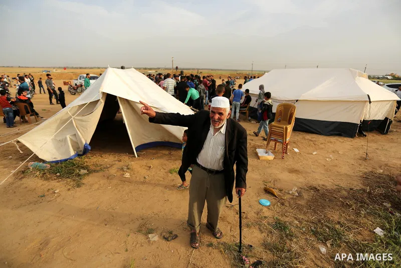 An elderly Palestinian man walks next to tents erected near the Gaza-Israel border on the outskirts of the Khan Yunis in the southern Gaza Strip on March 28, 2018. Protesters plan to call for the right of Palestinian ref...