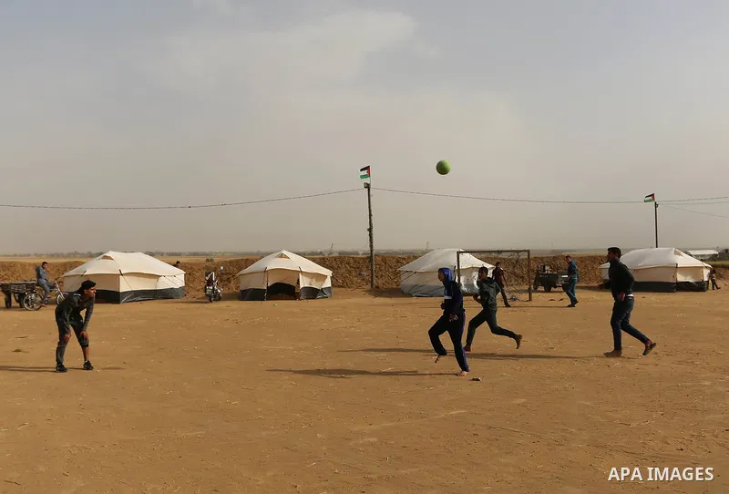 Paleatinians gather next to tents pitched by Palestinians on the Gaza border with Israel, in the southern Gaza Strip, on March 29, 2018, ahead of a six-week protest camp. The exceptional protest is dubbed "The Great Marc...