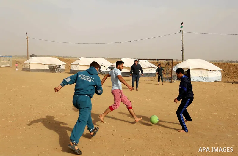 Paleatinians gather next to tents pitched by Palestinians on the Gaza border with Israel, in the southern Gaza Strip, on March 29, 2018, ahead of a six-week protest camp. The exceptional protest is dubbed "The Great Marc...