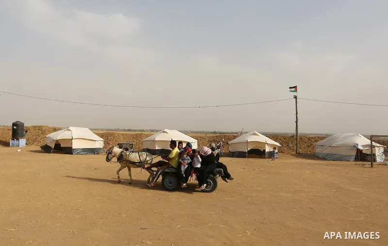 Paleatinians gather next to tents pitched by Palestinians on the Gaza border with Israel, in the southern Gaza Strip, on March 29, 2018, ahead of a six-week protest camp. The exceptional protest is dubbed "The Great Marc...